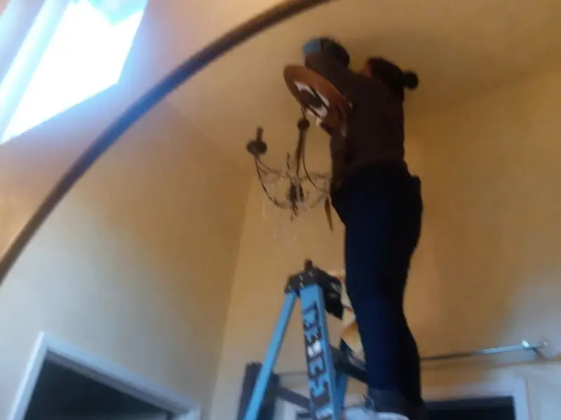 Electrician installing a chandelier in a Danbury residence